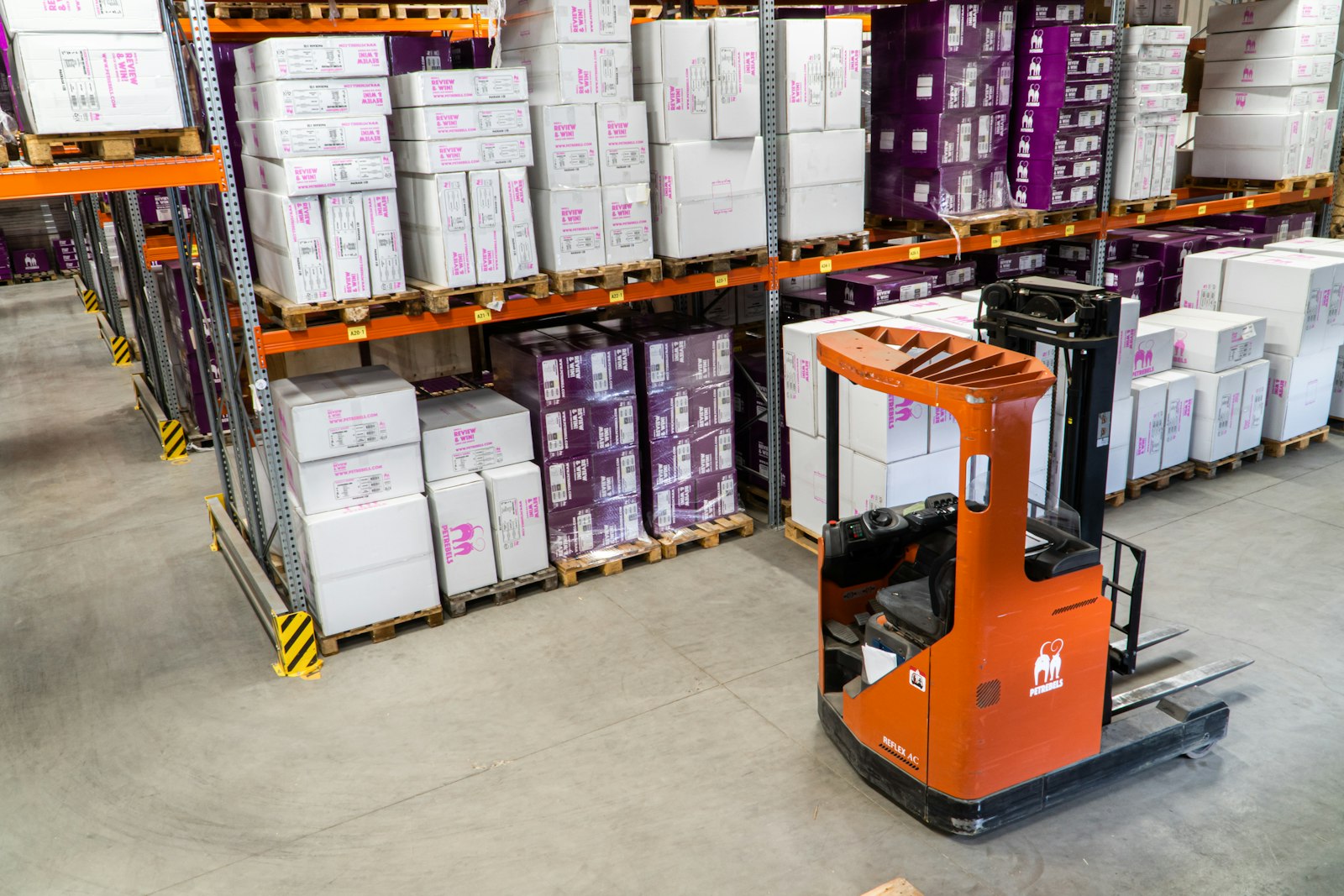 Warehouse racks stocked with boxed inventory and a forklift